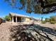 Large backyard with rock landscaping, mature trees, and a covered patio with seating at 11025 Hawk Valley Ave, Las Vegas, NV 89134