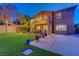 A spacious backyard featuring lush green turf, a covered patio, string lights, and a manicured garden at 112 Kava Kava St, Henderson, NV 89015