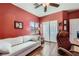 Bright bedroom with wood floors features a white couch, ceiling fan and an office space at 11253 Sanbury Brook St, Las Vegas, NV 89183