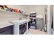 Bright laundry room featuring white front-load machines, storage shelves, and tiled flooring at 11253 Sanbury Brook St, Las Vegas, NV 89183