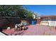 Red-tiled backyard with a brown fence, foliage, and assorted furniture under a clear blue sky at 1414 Rexford Pl, Las Vegas, NV 89104