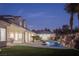 Backyard features an outdoor kitchen, covered patio, lush lawn, and a rock waterfall pool at 1865 Woodhaven Dr, Henderson, NV 89074