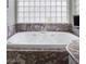 Spa-like soaking tub featuring marble surround, block glass window, and personal television at 1865 Woodhaven Dr, Henderson, NV 89074