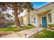 Well-maintained front yard featuring a walkway leading to a turquoise front door, lush landscaping, and mature trees at 2251 Van Gogh Dr, Henderson, NV 89074