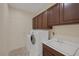 Functional laundry room featuring wood cabinetry, a utility sink, and a modern washer and dryer at 2295 Otter Rock Ave, Henderson, NV 89044