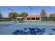 Well-maintained tennis court surrounded by lush greenery and shaded seating areas at 2295 Otter Rock Ave, Henderson, NV 89044