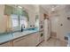 Bright kitchen boasts white cabinets, appliances, a sink, and a window with floral curtains at 2325 Sombrero Dr, Las Vegas, NV 89169