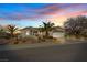 Inviting single-story home with a two-car garage, desert landscaping, and mature palm trees at sunset at 2862 Sapphire Desert Dr, Henderson, NV 89052