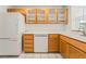 Bright kitchen featuring white appliances and wooden cabinets with glass fronts above the sink at 5025 Starfinder Ave, Las Vegas, NV 89108