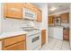Kitchen area with white appliances, wooden cabinets, and adjacent laundry area with washer and dryer at 5025 Starfinder Ave, Las Vegas, NV 89108