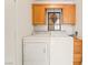 Convenient laundry area with a white washer and dryer, wooden cabinets, and decorative lighting fixture at 5025 Starfinder Ave, Las Vegas, NV 89108