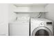 A white washer and dryer sit on a tile floor with shelves for storage at 5241 Caspian Springs Dr # 103, Las Vegas, NV 89120