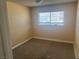 A simple bedroom with neutral walls, carpet flooring and natural light from the window at 5424 Del Rey Ave, Las Vegas, NV 89146