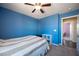 A bedroom features blue walls, carpet floors, a ceiling fan, and bright natural light at 5638 Jelsma Ave, Las Vegas, NV 89141