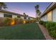 Expansive backyard lawn with lush plantings provides a serene outdoor space between neighboring residences at dusk at 616 Canyon Brook Pl, Las Vegas, NV 89145