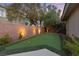 Private backyard featuring a putting green area, complemented by elegant landscaping, including mature trees and brick wall with lighting at 616 Canyon Brook Pl, Las Vegas, NV 89145
