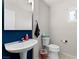 Modern half bath with pedestal sink, toilet, and stylish blue accent wall at 672 Peach Coral St, Las Vegas, NV 89183