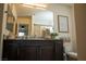 Well-lit bathroom with dark wood vanity, granite countertop, and decorative accessories at 6824 Satin Silver Ct, North Las Vegas, NV 89086