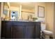 Well-lit bathroom with dark wood vanity, granite countertop, and decorative accessories at 6824 Satin Silver Ct, North Las Vegas, NV 89086