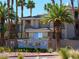 Beautiful multi-story building with lush landscaping, palm trees, and a decorative community sign at 7147 S Durango Dr # 211, Las Vegas, NV 89113
