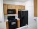 Functional kitchen with black appliances, oak cabinets, and tiled flooring, ideal for cooking at 7147 S Durango Dr # 211, Las Vegas, NV 89113