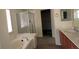Bathroom featuring a large bathtub, glass-enclosed shower, stylish sink and vanity, perfect for relaxation at 8768 Charm Canyon Ave, Las Vegas, NV 89178