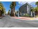 Street view of a gated community entrance featuring modern signage and tropical landscaping at 9050 W Tropicana Ave # 1053, Las Vegas, NV 89147
