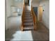 Entryway and staircase offers a view into the living space, with carpeted floors and wooden railings at 9641 Windborne Ave, Las Vegas, NV 89147