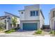 Contemporary two-story home with gray stucco exterior, a blue-green garage door, and xeriscaped front yard at 9772 Alpine Style Dr, Las Vegas, NV 89166