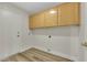 Well-lit laundry room with wood floors, upper cabinets for storage, and hookups for a washer and dryer at 9962 Catalina Canyon Ave, Las Vegas, NV 89147