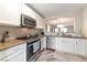 Well-lit kitchen features stainless steel appliances, white cabinets, and stylish gray-toned flooring at 10741 Pearl River Ave, Las Vegas, NV 89166