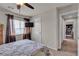 Well-lit bedroom with a ceiling fan, mounted television, and view into the hallway from the comfortable sleeping space at 1161 Sax Fifth Ave, Henderson, NV 89052