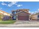 Two-story home featuring a brown facade, two-car garage, and a well-maintained lawn at 1481 Rancho Ridge Dr, Henderson, NV 89012