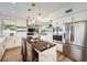 Open kitchen with white cabinets, wooden island seating, stainless steel appliances, and view to living area at 150 Wentworth Dr, Henderson, NV 89074