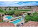An elevated view of a backyard with a swimming pool, hot tub, lush landscaping, and a view of the golf course at 150 Wentworth Dr, Henderson, NV 89074