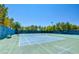 A well-maintained tennis court surrounded by lush greenery and a tall fence, perfect for recreational play at 150 Wentworth Dr, Henderson, NV 89074