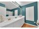 Well lit bathroom with teal walls, long white counter, double sinks and updated hardware at 1848 Indian Bend Dr, Henderson, NV 89074
