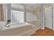 Bright bathroom features a walk-in shower, glass block window, and tiled soaking tub with jets at 1848 Indian Bend Dr, Henderson, NV 89074