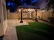 A backyard pergola lit with string lights sits adjacent to an artificial lawn at 3794 Cape Royal St, Las Vegas, NV 89147