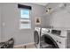 Laundry room with modern washer and dryer, overhead shelving, and a window at 397 Purple Sandpiper St, Las Vegas, NV 89138