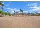A vast dirt yard surrounded by trees, shrubs and mature palm trees offers a blank canvas for landscaping at 5890 W Patrick Ln, Las Vegas, NV 89118