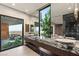 Bright bathroom with a marble countertop, dual sinks, and a large window overlooking a landscaped outdoor area at 6 Vista Crescent Ct, Henderson, NV 89012