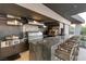 Well-equipped outdoor kitchen featuring stainless steel appliances, granite counters, bar seating and elegant backsplash at 6 Vista Crescent Ct, Henderson, NV 89012