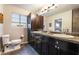Bathroom featuring a dual sink vanity, dark wood cabinets, dark granite countertops, and tile flooring at 650 Arizona St, Boulder City, NV 89005