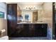 Bathroom featuring a dual sink vanity, dark wood cabinets, dark granite countertops, and tile flooring at 650 Arizona St, Boulder City, NV 89005