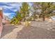 Backyard has desert landscaping with a small fire pit feature, block wall, and mature trees at 7140 Pascal Dr, Las Vegas, NV 89156