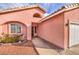 Home's entrance featuring low-water landscaping with decorative rock, barrel tile roof, and two car garage at 7140 Pascal Dr, Las Vegas, NV 89156