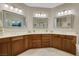Bright bathroom features double sinks, wood cabinets, neutral tile, and decorative framed mirrors at 7307 Lansbrook Ave, Las Vegas, NV 89131