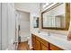 Bright bathroom with a large framed mirror, wood cabinets and a shower over tub at 7307 Lansbrook Ave, Las Vegas, NV 89131