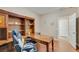 Home office features a built-in wooden desk, shelving, wood floors and a comfortable chair at 7307 Lansbrook Ave, Las Vegas, NV 89131